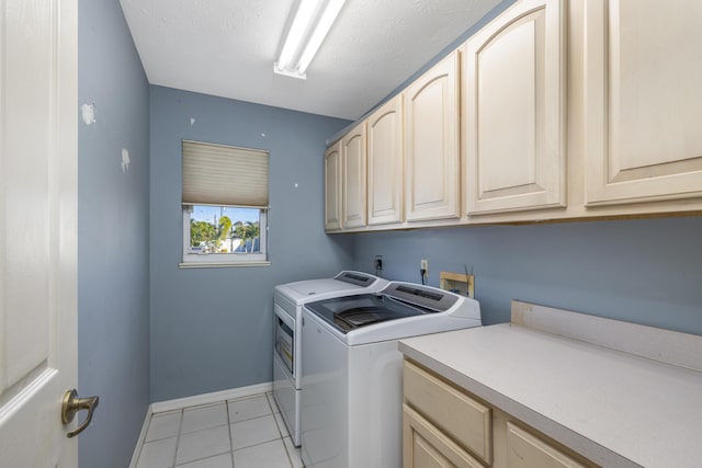 laundry area with cabinets, light tile patterned floors, a textured ceiling, and washer and clothes dryer