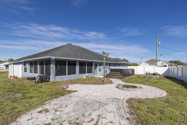 back of house featuring a patio area, an outdoor fire pit, a lawn, and a sunroom