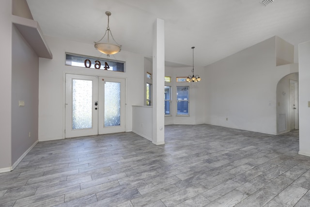 entryway with french doors, light wood-type flooring, and an inviting chandelier