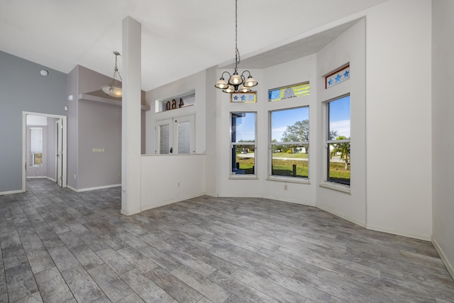 interior space with a towering ceiling, a chandelier, and hardwood / wood-style flooring