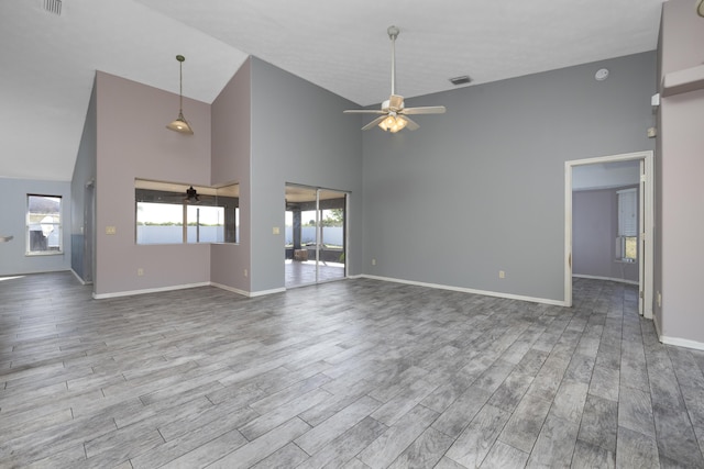 unfurnished living room with ceiling fan, high vaulted ceiling, and light hardwood / wood-style floors