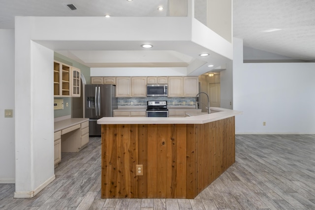 kitchen with a center island, light hardwood / wood-style floors, light brown cabinets, and appliances with stainless steel finishes