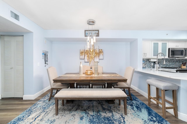 dining space with a notable chandelier, wood-type flooring, and sink