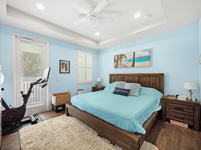 bedroom with ceiling fan, a raised ceiling, and access to outside