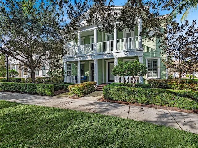 view of front facade with a balcony and a front lawn