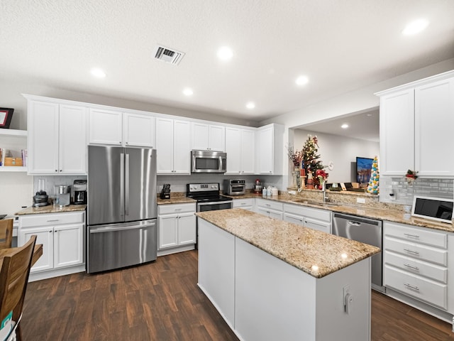 kitchen with stainless steel appliances, sink, a kitchen island, and white cabinets