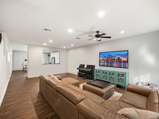 living room featuring wood-type flooring, ceiling fan, and a textured ceiling