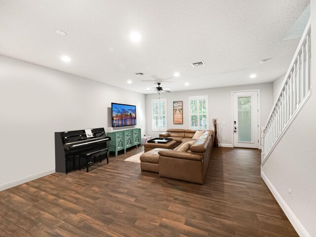 living room featuring a textured ceiling, dark wood-type flooring, and ceiling fan