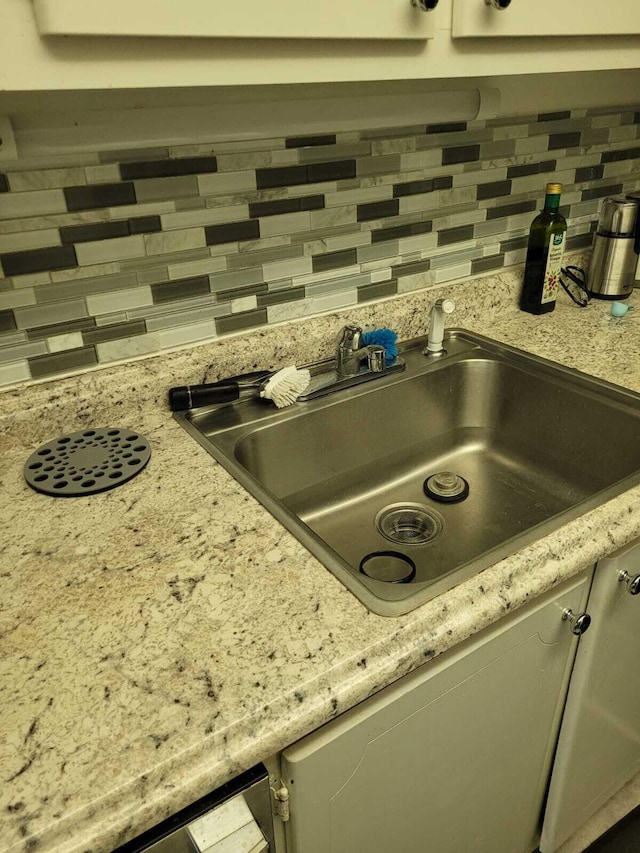 interior details with decorative backsplash, light stone counters, and sink