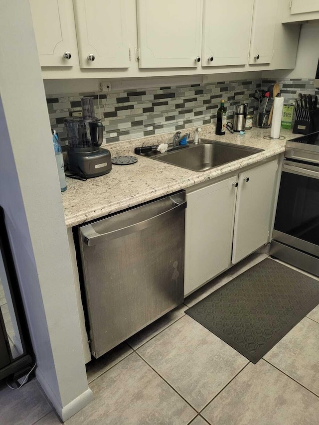 kitchen featuring appliances with stainless steel finishes, backsplash, sink, white cabinets, and light tile patterned flooring