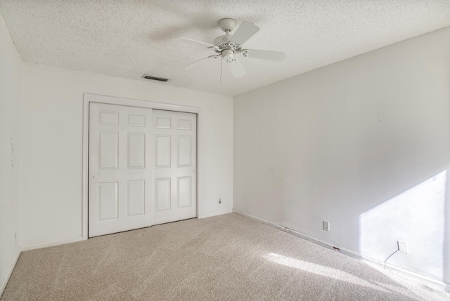 unfurnished bedroom featuring ceiling fan, carpet floors, a textured ceiling, and a closet