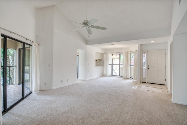 unfurnished living room featuring high vaulted ceiling, light colored carpet, and ceiling fan with notable chandelier