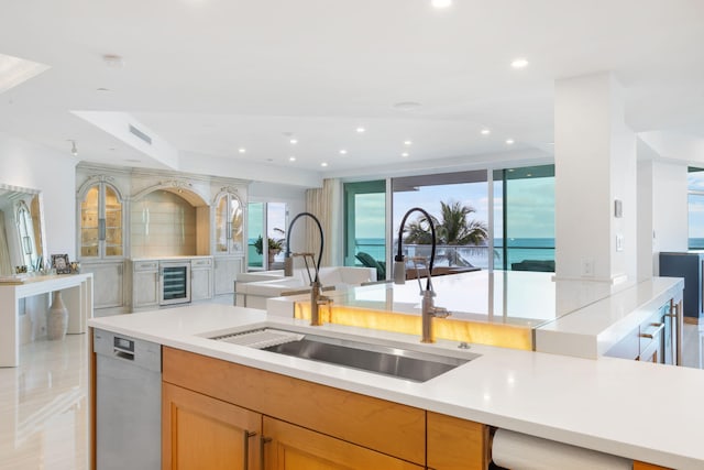 kitchen featuring stainless steel dishwasher, floor to ceiling windows, beverage cooler, sink, and a water view