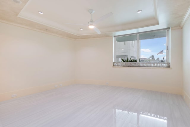 unfurnished room with a tray ceiling, ceiling fan, and ornamental molding