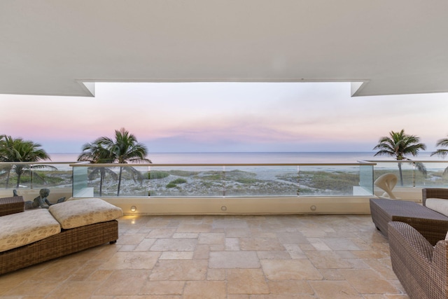 balcony at dusk featuring a water view