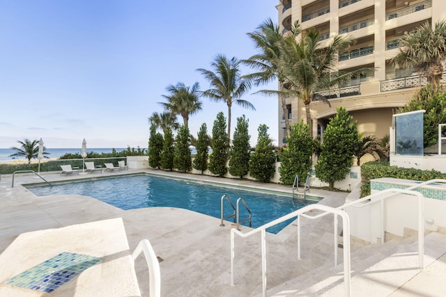 view of swimming pool featuring a patio and a water view