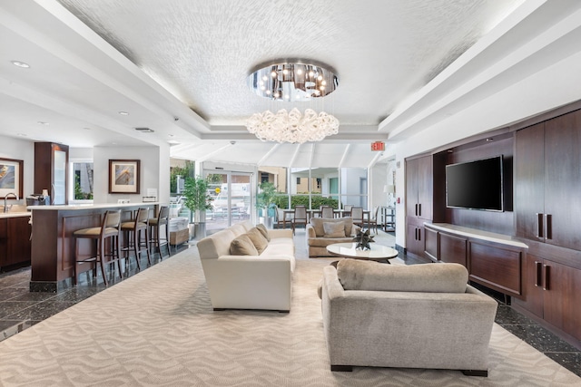 living room with a raised ceiling and a notable chandelier