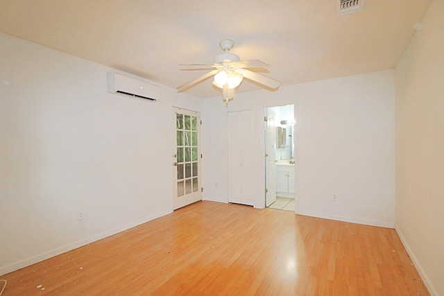 unfurnished room featuring an AC wall unit, ceiling fan, and light hardwood / wood-style flooring