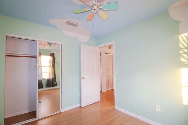 unfurnished bedroom featuring a closet, light hardwood / wood-style flooring, and ceiling fan