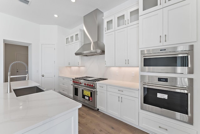 kitchen with white cabinetry, wall chimney range hood, sink, and appliances with stainless steel finishes