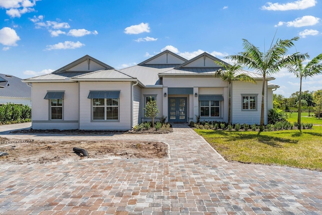 view of front of home with decorative driveway, french doors, and metal roof