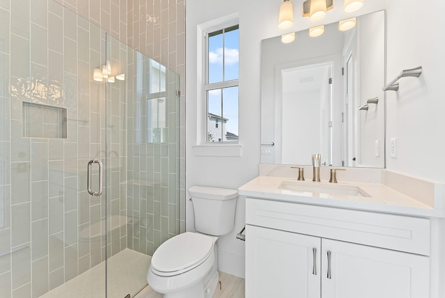 bathroom with vanity, hardwood / wood-style flooring, toilet, and a shower with door