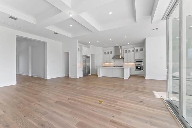 unfurnished living room featuring beam ceiling, light wood-type flooring, sink, and coffered ceiling