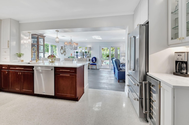 kitchen featuring sink, beverage cooler, stainless steel appliances, a notable chandelier, and pendant lighting