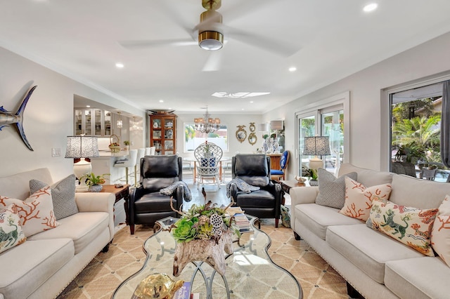 living room with ceiling fan with notable chandelier and ornamental molding