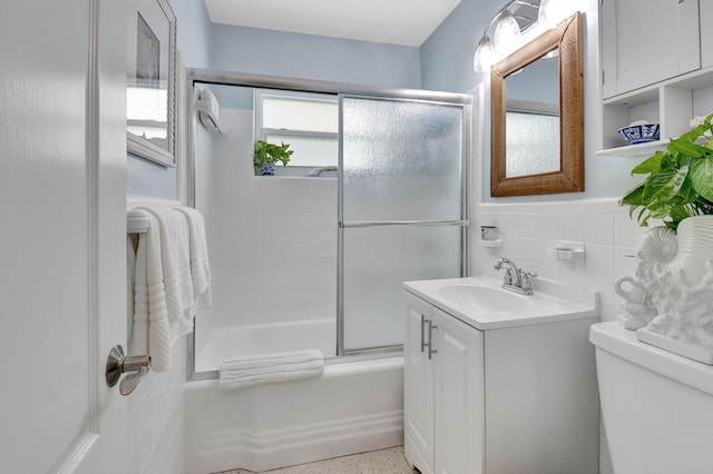 full bathroom featuring shower / bath combination with glass door, vanity, tile walls, and toilet