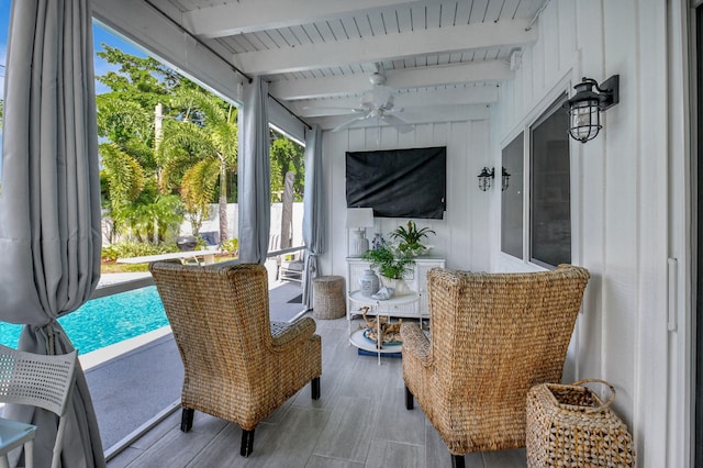 sunroom featuring beamed ceiling and ceiling fan