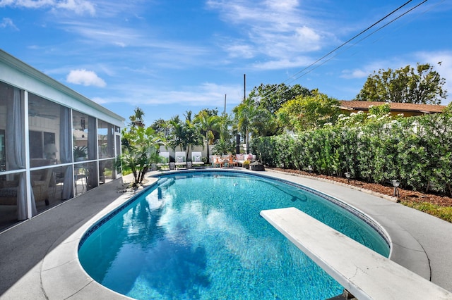 view of pool featuring a sunroom and a diving board