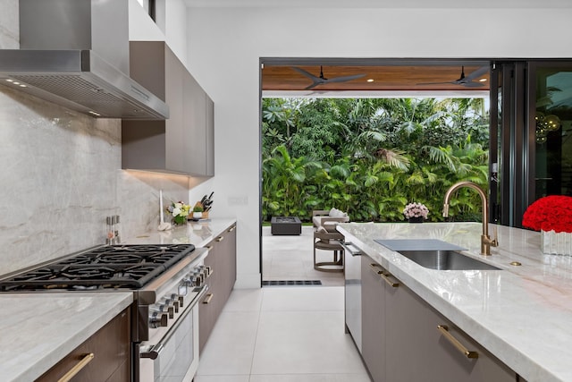 kitchen featuring stainless steel appliances, sink, light stone counters, wall chimney exhaust hood, and gray cabinetry