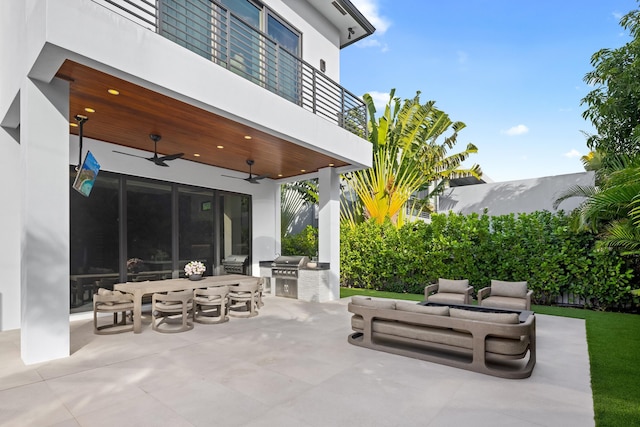 view of patio / terrace with a balcony, a grill, ceiling fan, outdoor lounge area, and exterior kitchen