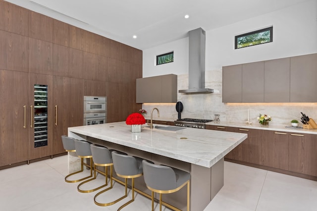 kitchen with a kitchen breakfast bar, an island with sink, ventilation hood, and light tile patterned floors