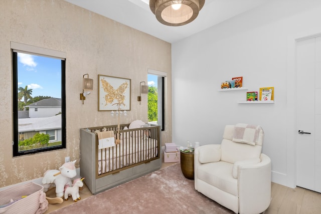 bedroom with a nursery area and light hardwood / wood-style flooring