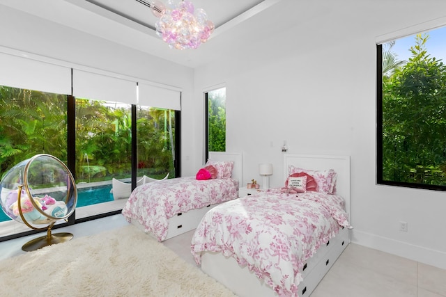 bedroom featuring a notable chandelier, a tray ceiling, and light tile patterned floors