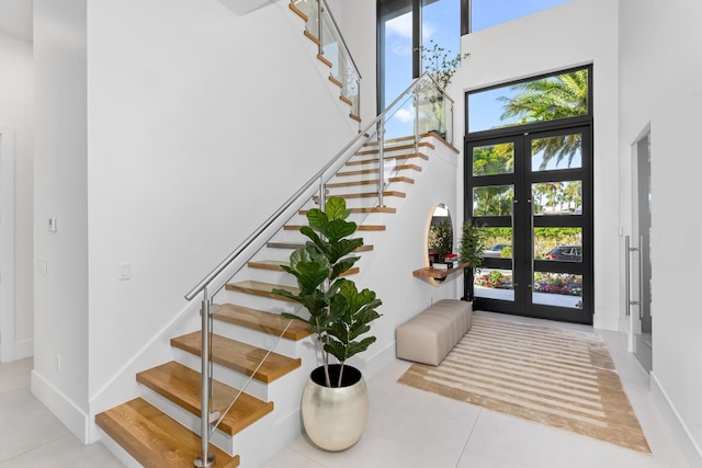 entryway with a towering ceiling, french doors, a wealth of natural light, and light tile patterned floors