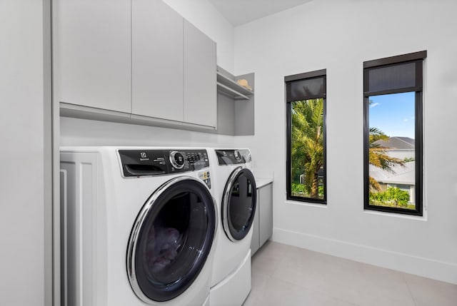 clothes washing area featuring light tile patterned floors, separate washer and dryer, and cabinets