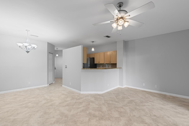 unfurnished living room featuring ceiling fan with notable chandelier