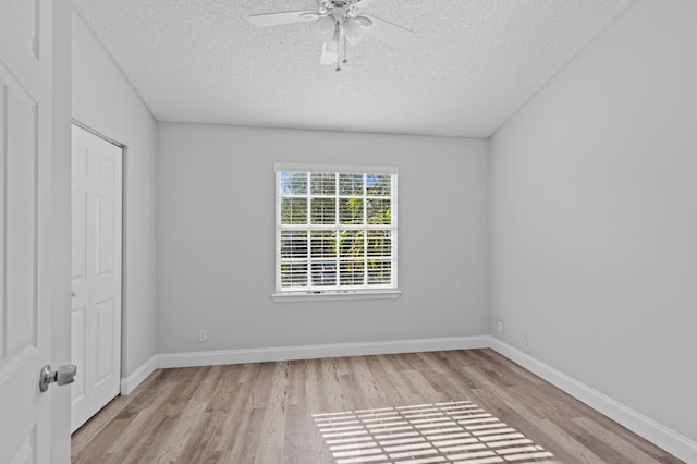 empty room with ceiling fan, light hardwood / wood-style flooring, and a textured ceiling