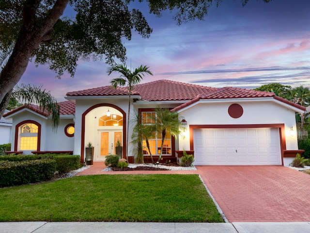 mediterranean / spanish-style house featuring a garage and a yard