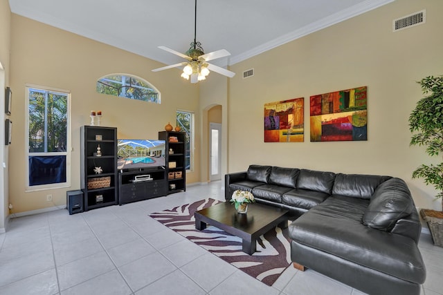 tiled living room with ceiling fan and crown molding