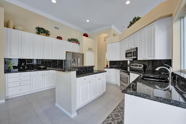 kitchen with white cabinetry, appliances with stainless steel finishes, light tile patterned flooring, dark stone counters, and a kitchen island