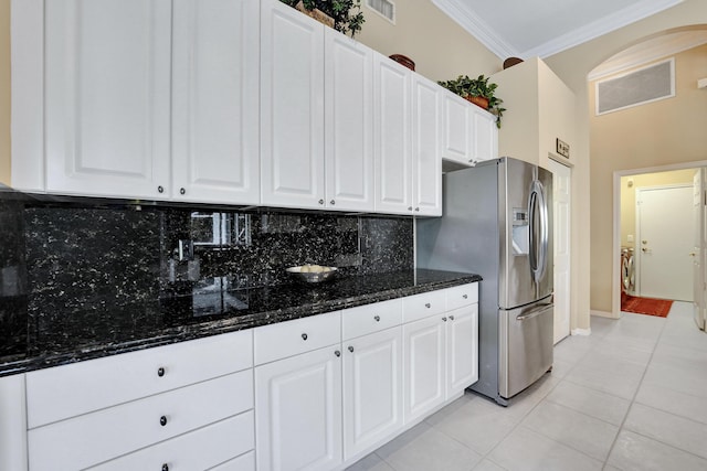 kitchen featuring stainless steel refrigerator with ice dispenser, light tile patterned flooring, white cabinetry, and dark stone countertops