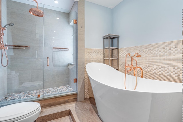 bathroom with hardwood / wood-style flooring, separate shower and tub, toilet, and tile walls