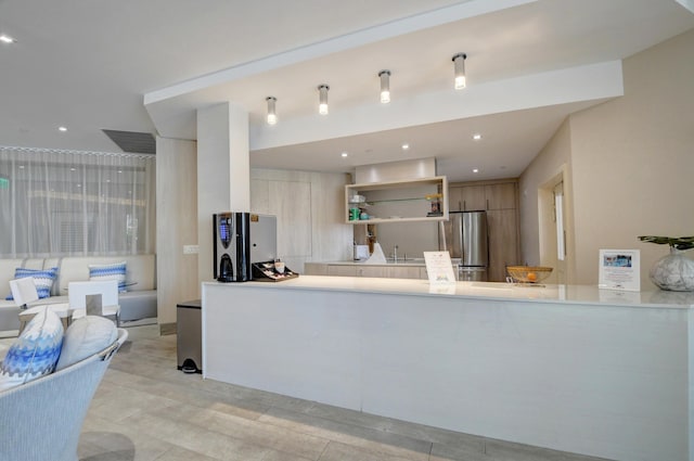 kitchen featuring stainless steel fridge, kitchen peninsula, and sink