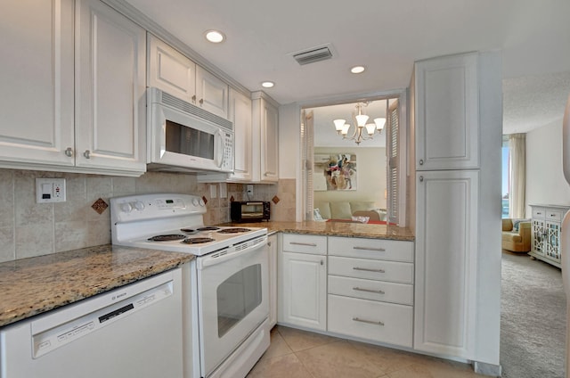 kitchen featuring light stone countertops, light tile patterned flooring, a notable chandelier, white appliances, and white cabinets