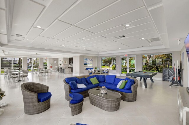 living room featuring a raised ceiling, a wealth of natural light, light tile patterned floors, and billiards