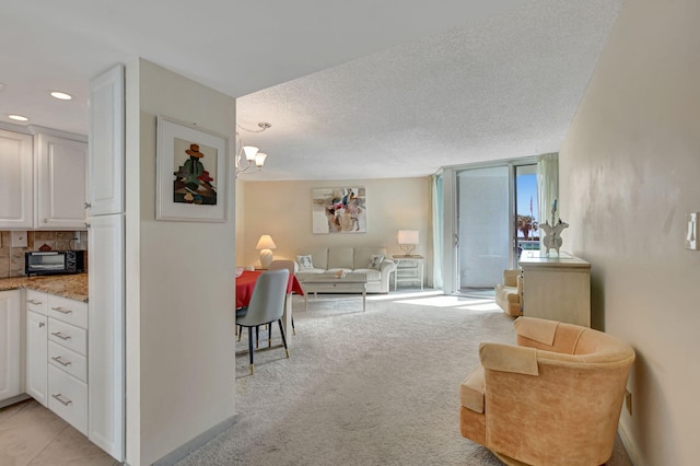 living room with floor to ceiling windows, a textured ceiling, light carpet, and a chandelier